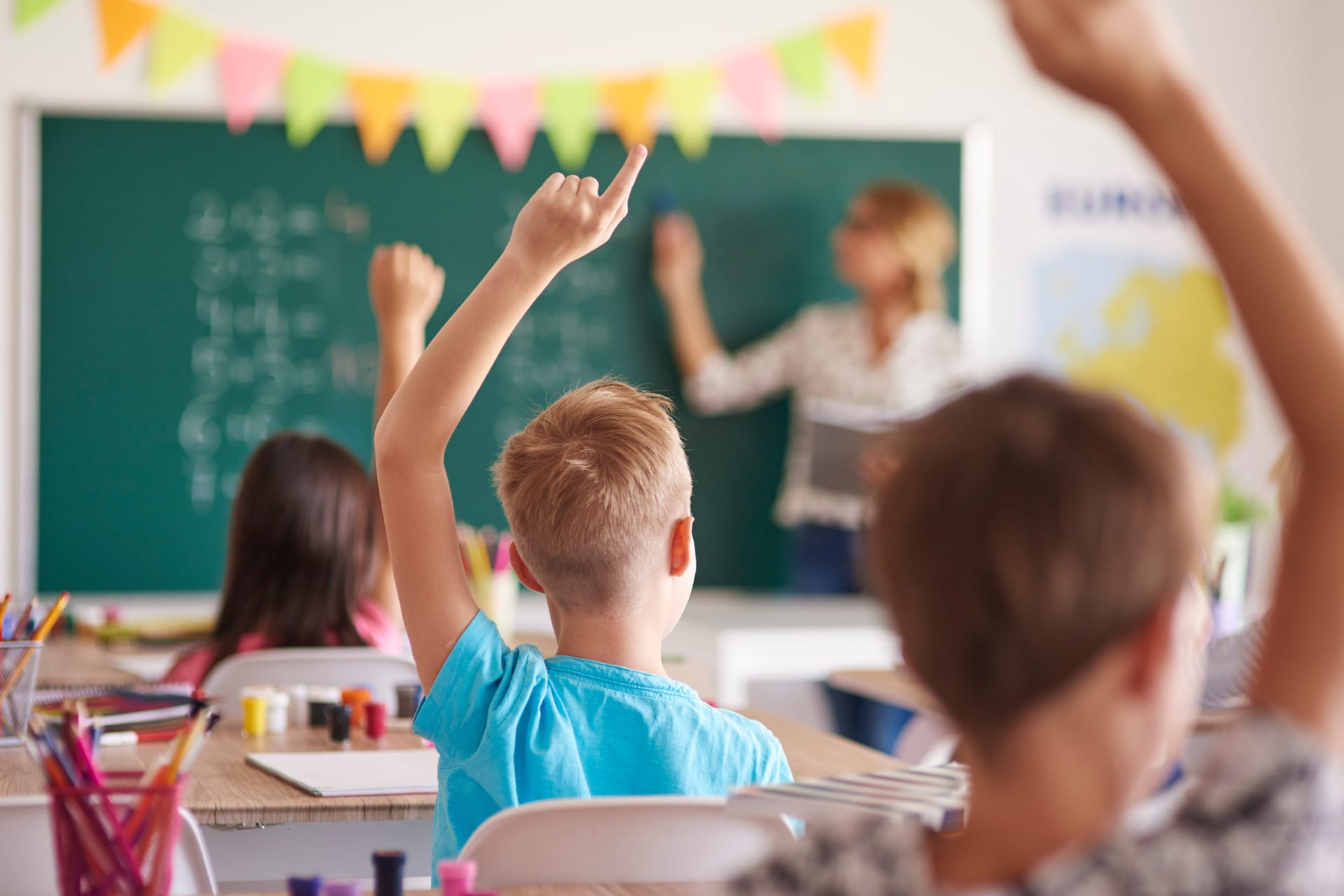 children raising their hands in a classroom